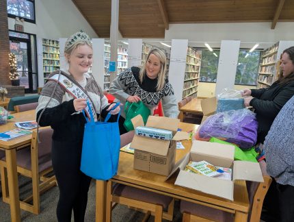 Penelope Murphy, Sarah Keiper, and Sarah Miles fill tote bags with books for attendees.